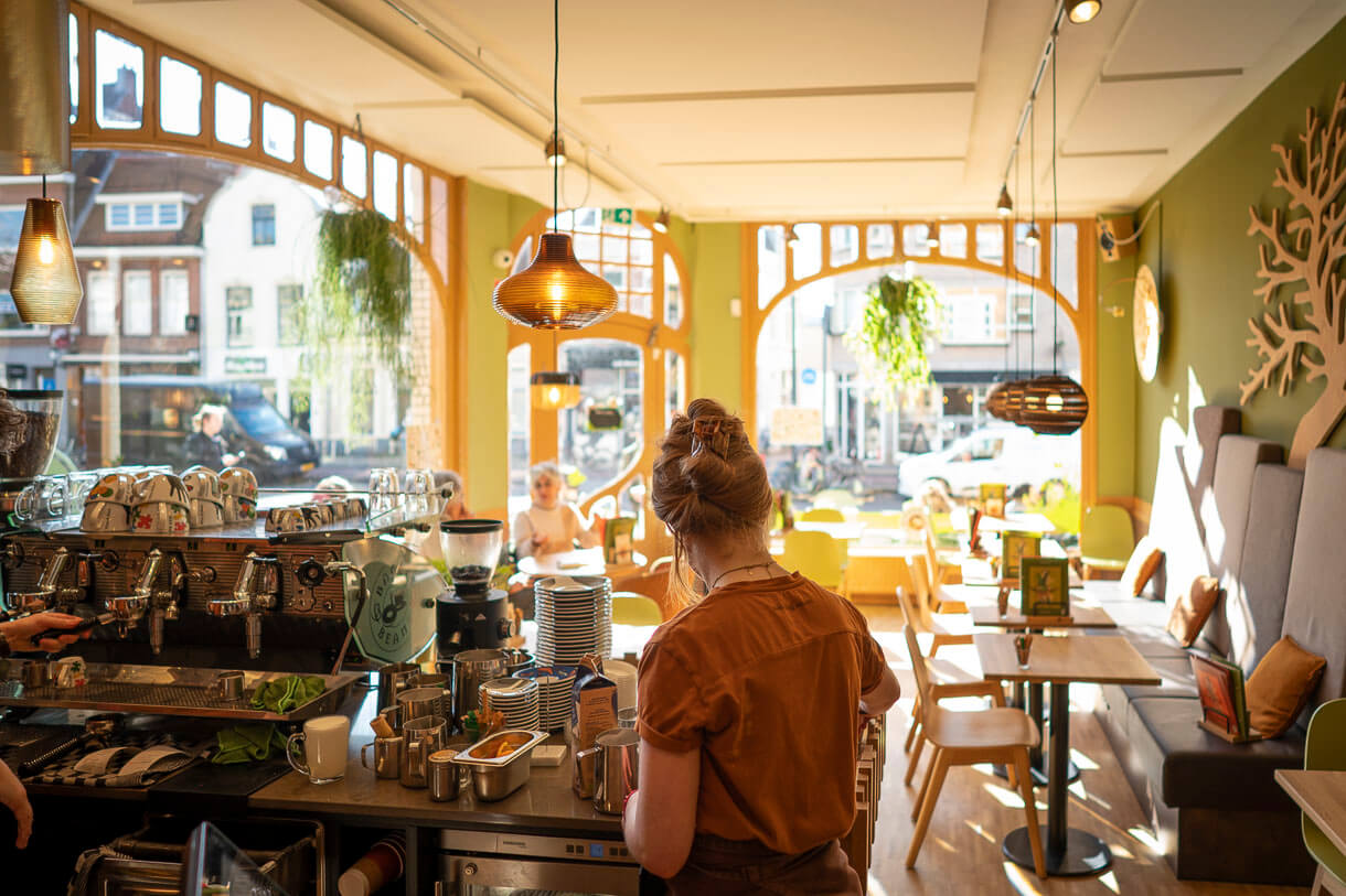 Interieur van een Bagels & Beans met veel licht, grote ramen en uitzicht op de stad