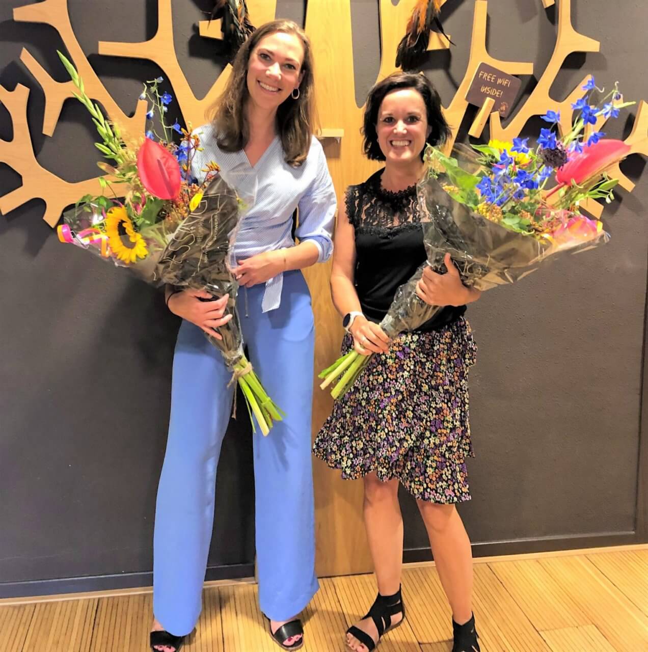 Twee franchisers worden gefeliciteerd met een grote bos bloemen