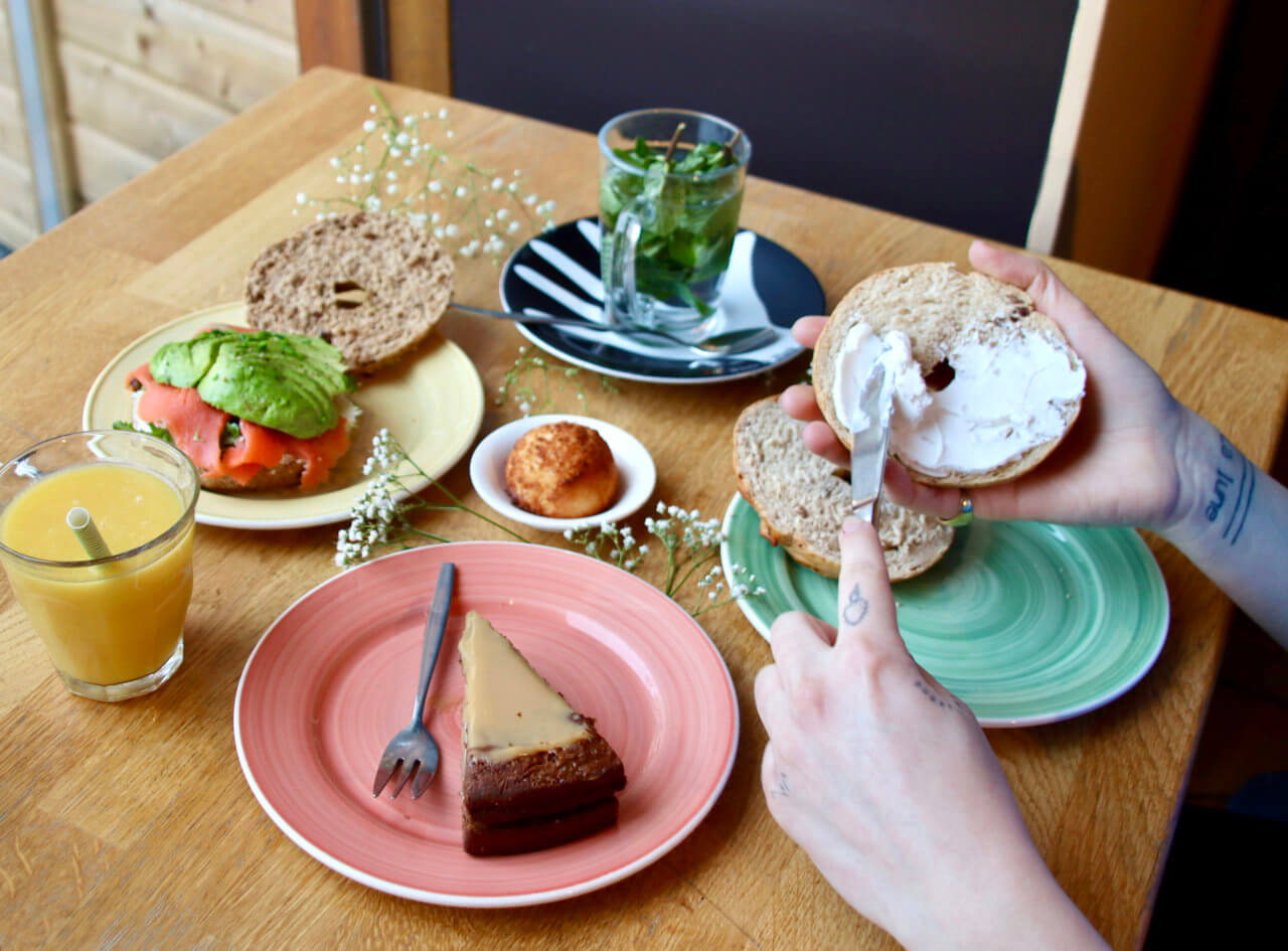 Een goed gevulde tafel met bagels, taart en thee.